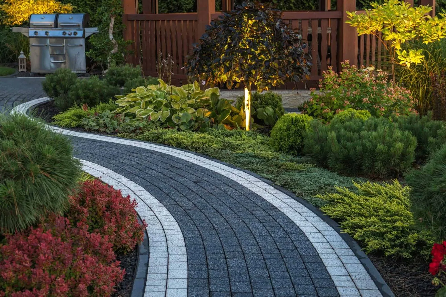 Curved charcoal paver walkway landscape uplighting dusk