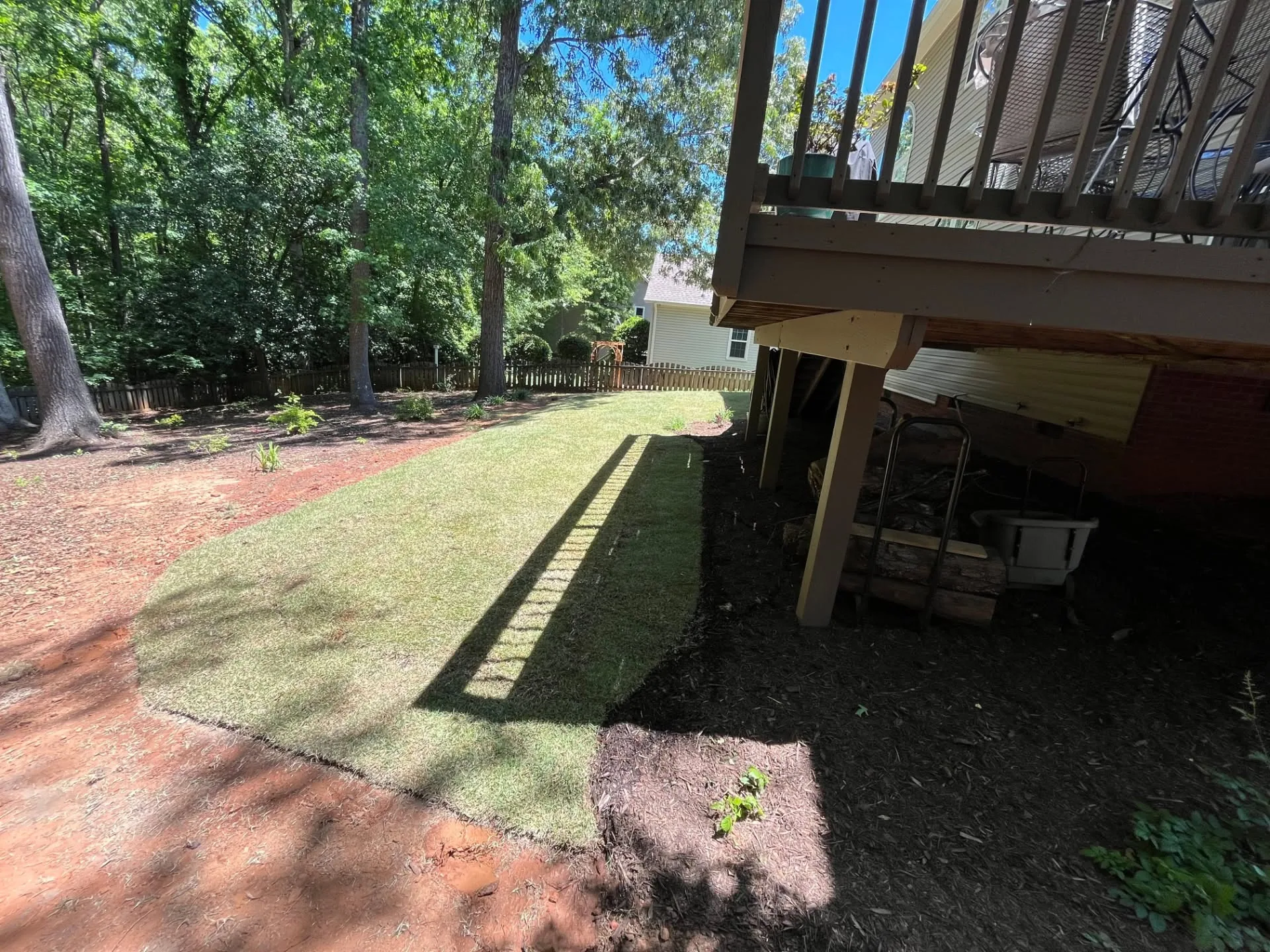 Curved sod strip mulched under deck wooded backyard.d2e479af