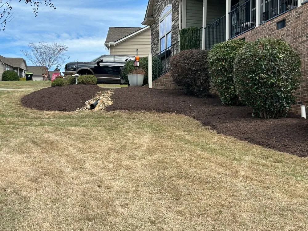 Downspout drain river rock brown mulch bed slope