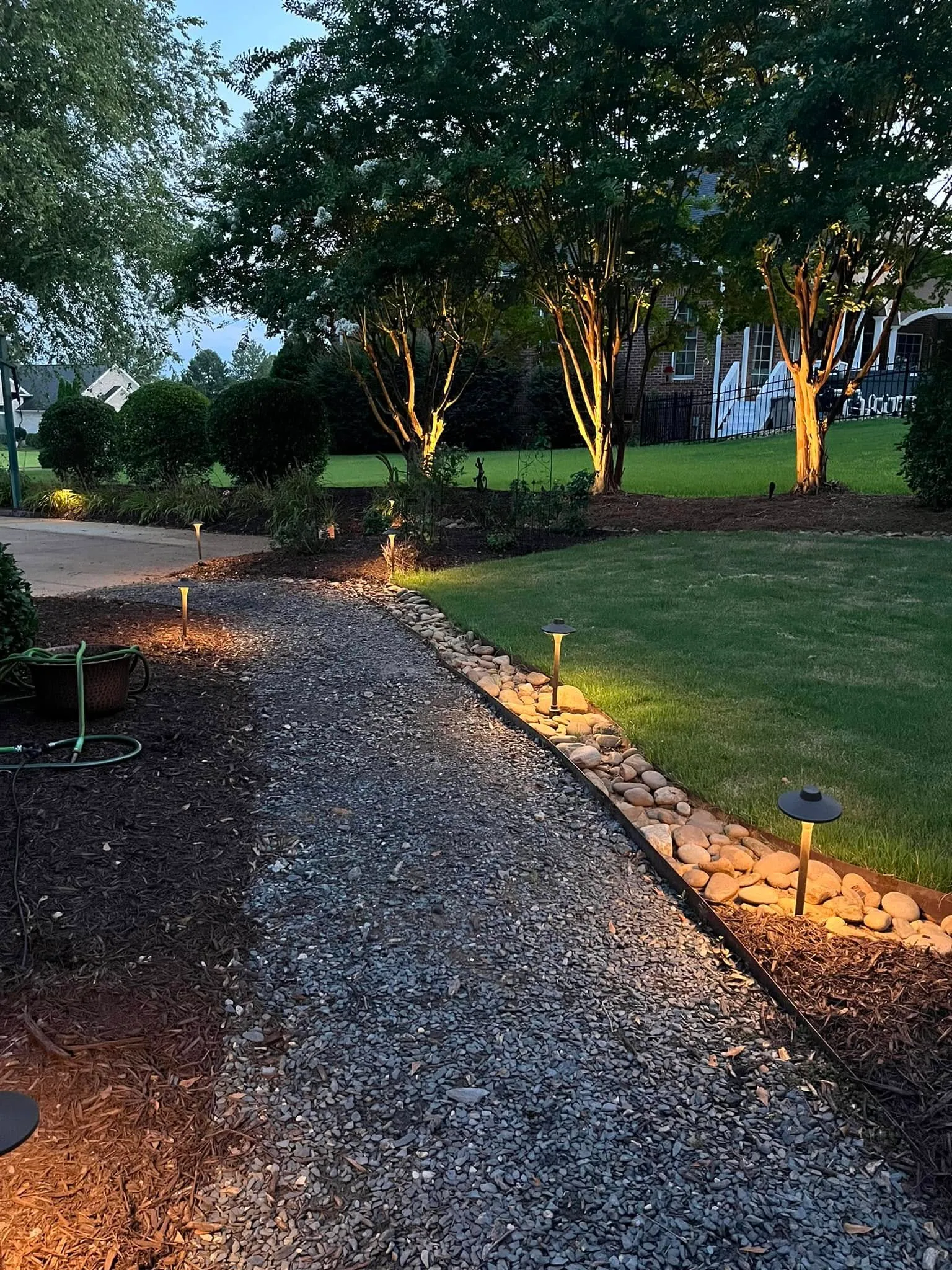 Gravel path landscape lighting river rock border dusk