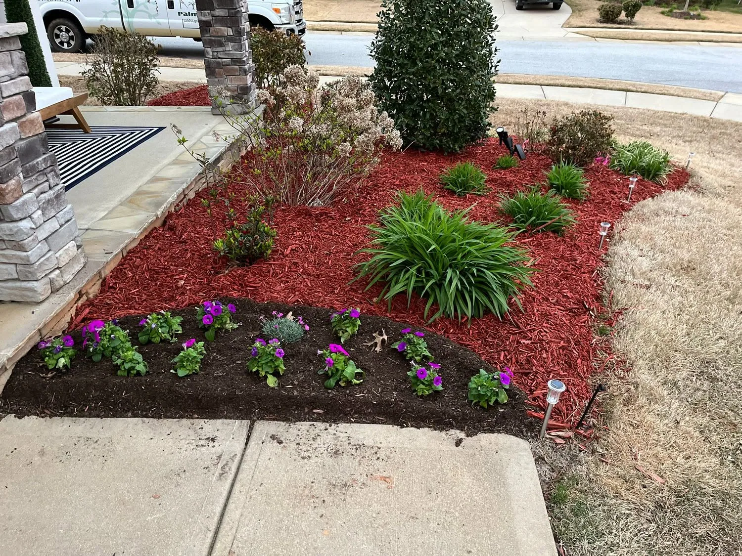 Purple annuals red mulch bed stone porch columns