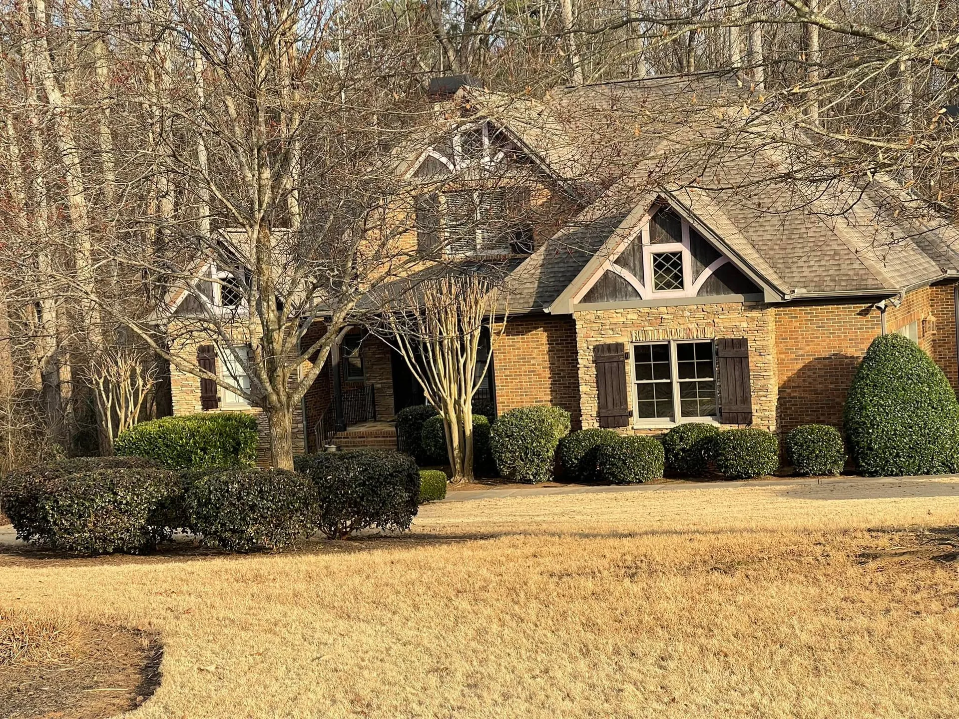 Rounded evergreen shrubs stone brick home winter