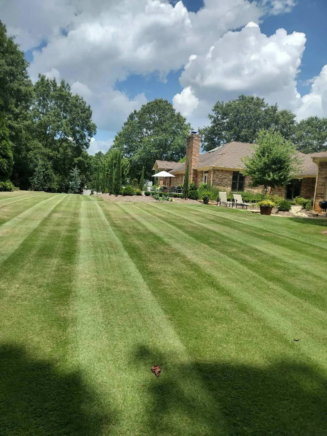 Striped backyard lawn mowing brick ranch home.90b54510