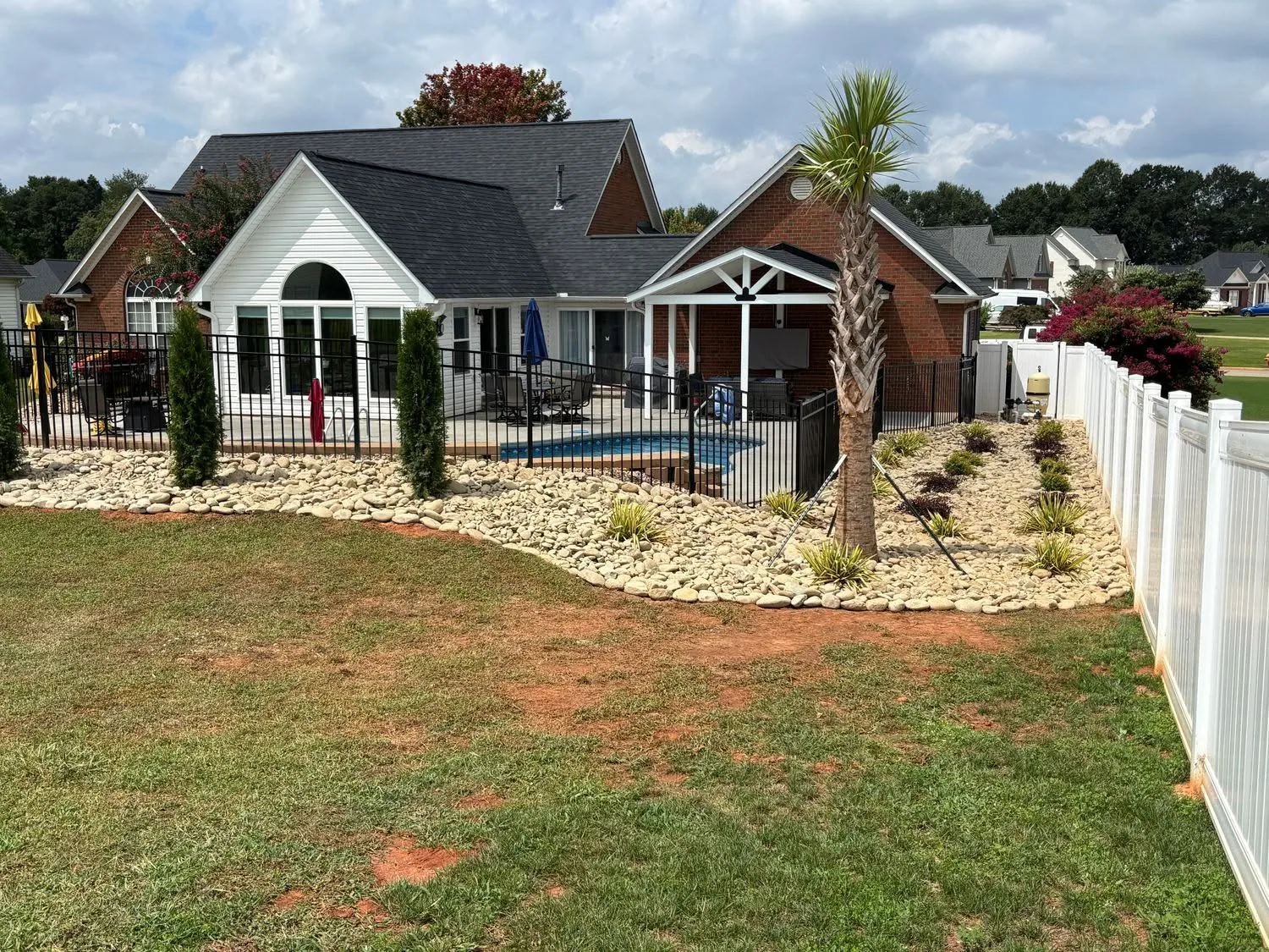 Wide backyard staked palm river rock vinyl fence.ab6c0a7e